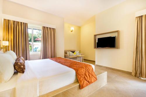 a hotel room with a bed and a flat screen tv at Club Mahindra Arookutty, Alleppey in Alleppey