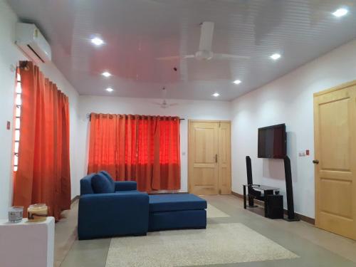 a living room with a blue couch and a television at Lovely 3-bedroom vacation home in Kumasi in Kumasi