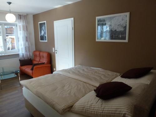 ein Schlafzimmer mit einem Bett und einem orangenen Stuhl in der Unterkunft Haus Irlinger in Schönau am Königssee