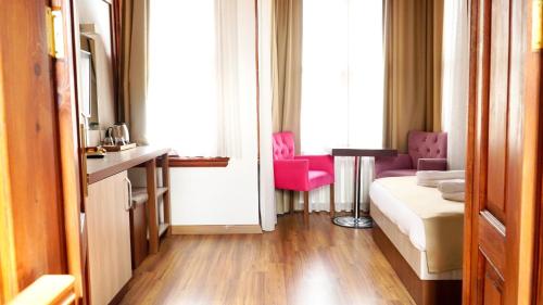 a living room with a couch and two pink chairs at QONAQ HOTEL & SUITES in Istanbul