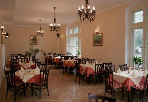 een eetkamer met tafels en stoelen en een kroonluchter bij Pension Sanssouci in Potsdam