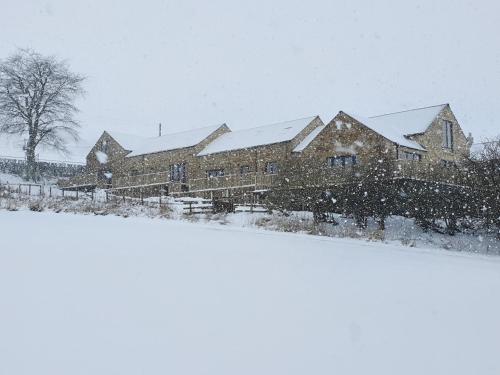 a house covered in snow in a field at Valley View Cottage in Rothbury