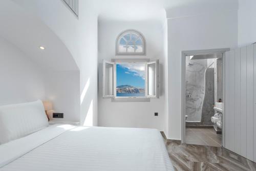 a white bedroom with a bed and a window at Sole d'oro Sunset & Caldera View Grand Suite in Oia