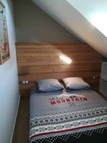 - un lit avec une tête de lit en bois dans l'établissement Le Gîte de la Maison Soleil, entre lac et montagne, à Alex