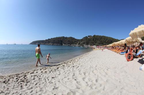 a man and a child walking on the beach at Hotel Lo Scirocco in Campo nell'Elba