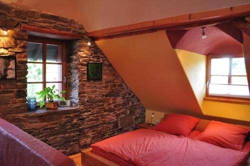 een slaapkamer met een bed en een stenen muur bij Lehmlounge in Monschau