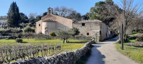 a stone building and a road next to a vineyard at Villa Lei Rigaü in Salernes