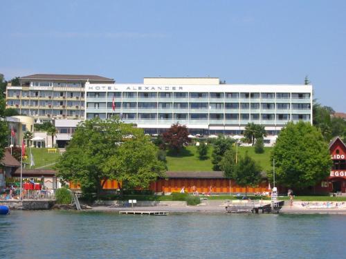 a large white building next to a body of water at Hotel Alexander in Weggis