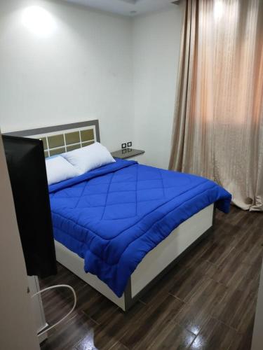 a bedroom with a bed with a blue comforter and a television at Ramco For Furnished Apartments And Accommodation Compound Leila in Cairo