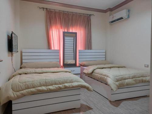 two beds sitting in a room with a window at Ramco For Furnished Apartments And Accommodation Compound Leila in Cairo