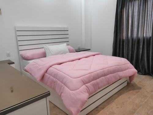 a bed with a pink comforter in a room at Ramco For Furnished Apartments And Accommodation Compound Leila in Cairo