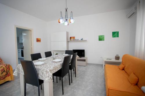 a dining room with a table and chairs and a couch at Villetta Emma in Torre Lapillo