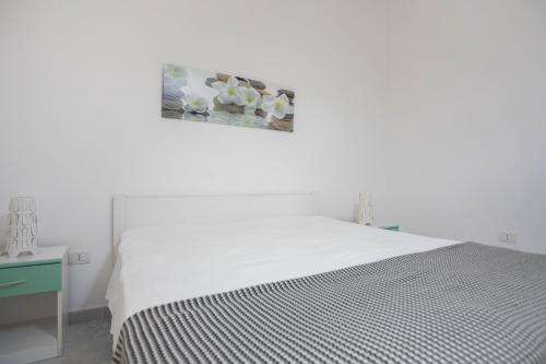 a white bedroom with a bed and a picture on the wall at Villetta Emma in Torre Lapillo