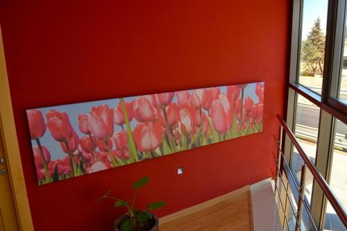 a painting of pink tulips on a red wall at Hotel El Cruce Moraleda in Moraleda de Zafayona
