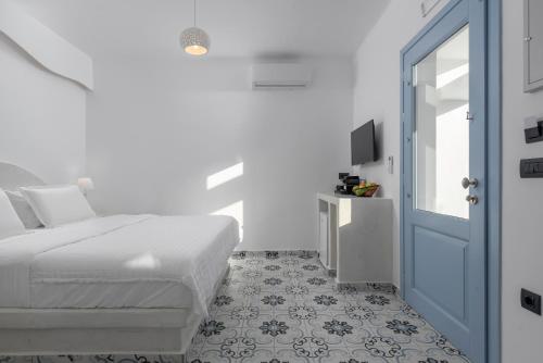 a white bedroom with a bed and a blue door at Sole d'oro Luxury Suites in Oia