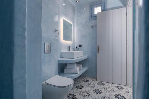 a bathroom with a white toilet and a sink at Sole d'oro Luxury Suites in Oia