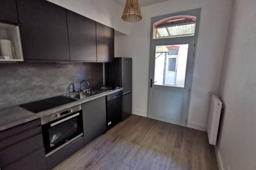 a kitchen with black cabinets and a sink and a window at La Maison de Timothée 11 couchages in Reims