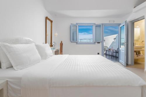 a white bedroom with a large white bed at Sole d'oro Luxury Suites in Oia