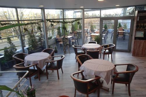 un ristorante con tavoli, sedie e finestre di Hotel Nord a Ploieşti