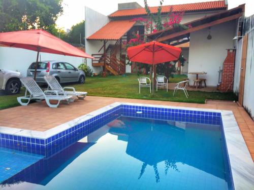 a swimming pool with chairs and umbrellas and a house at Casa do Francês Temporada in Maceió