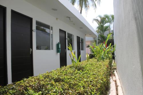 a white building with black doors and green bushes at Hotel Manantial Melgar Torre 2 in Melgar