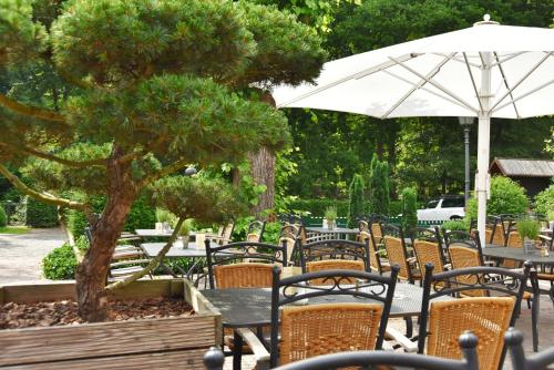 a table and chairs with a tree and an umbrella at Klosterschänke Hude Hotel Ferienwohnungen Restaurant Café in Hude
