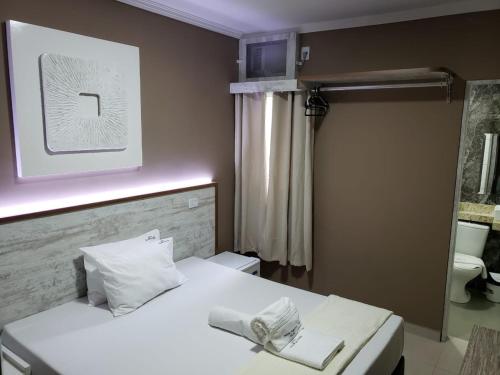 a bedroom with a white bed and a mirror at Hotel Recanto das Perdizes in Sao Paulo