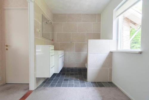 a bathroom with white cabinets and a sink and a window at B&B Het Zonnehuis Boxtel in Boxtel