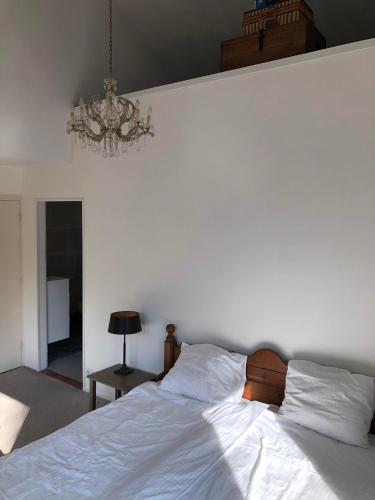 a bedroom with a white bed and a chandelier at B&B Het Zonnehuis Boxtel in Boxtel