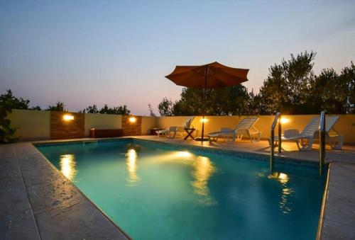 a swimming pool with chairs and an umbrella at Apartments Marjanovic in Vodice