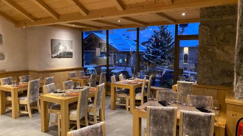 a restaurant with tables and chairs and a large window at La Pointe Percée in Le Grand-Bornand