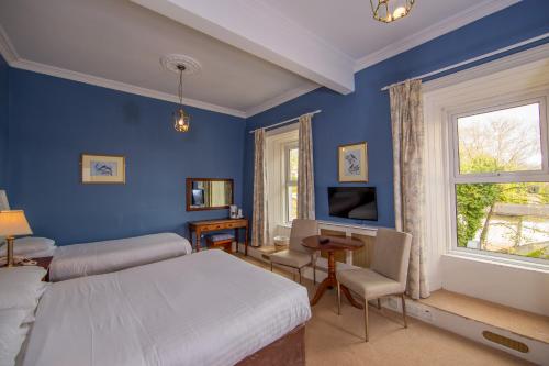 een slaapkamer met blauwe muren en een bed en een raam bij Foyles Hotel in Clifden