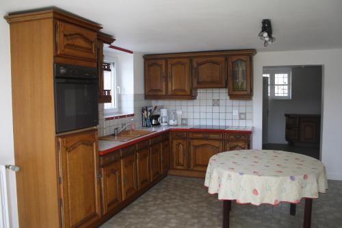 une cuisine avec des armoires en bois et une table à l'intérieur dans l'établissement Gîte du courtil aux fées, à Saint-Laurent
