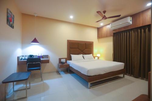 1 dormitorio con cama, silla y escritorio en Hotel Central Avenue en Sāngli