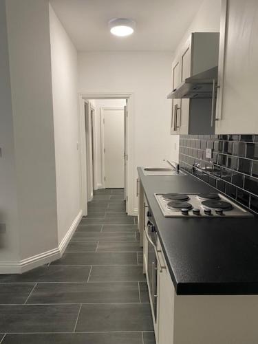 a kitchen with a black counter top and white cabinets at Nantwich House in Crewe