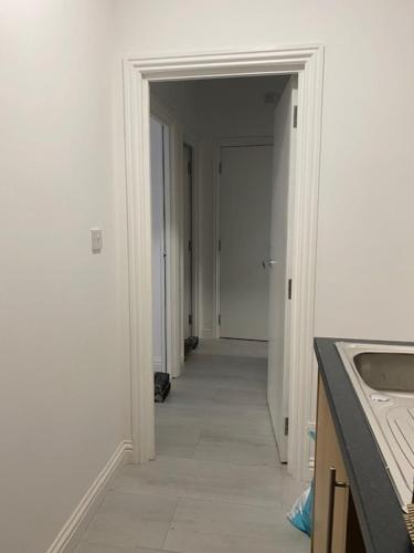 a hallway leading to a kitchen with a sink and a door at Nantwich House in Crewe