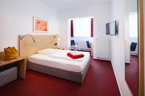 a hotel room with a bed and a tv at Hotel Haus vom Guten Hirten in Münster