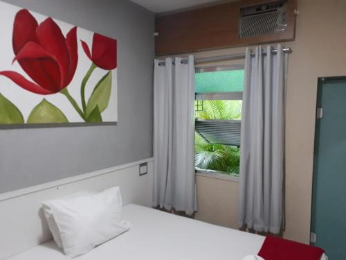 a bedroom with a bed and a window with a painting at Hotel Recanto das Perdizes in São Paulo