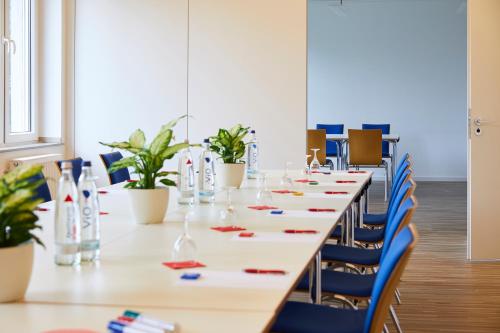 a long table in a room with blue chairs at Hotel Haus vom Guten Hirten in Münster