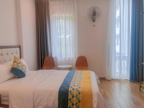 a bedroom with a bed with two chairs and windows at Swan Hotel in Ho Chi Minh City