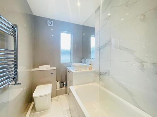 ein weißes Badezimmer mit einer Badewanne, einem WC und einem Waschbecken in der Unterkunft Cardonald Central in Glasgow