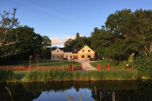 a house with a fence next to a body of water at Canal bank house in Bellanaboy