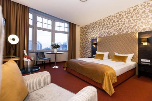 Habitación de hotel con cama y sofá en Royal International Leipzig, en Leipzig