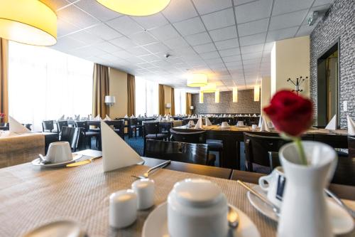 a restaurant with a table with a flower in a vase at Royal International Leipzig in Leipzig