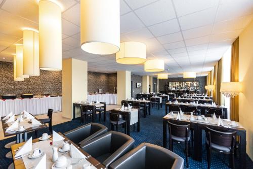 une salle à manger avec des tables, des chaises et des lustres dans l'établissement Royal International Leipzig, à Leipzig