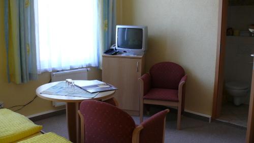 a room with a tv and a table and chairs at Pension Kreisel in Bad Kösen