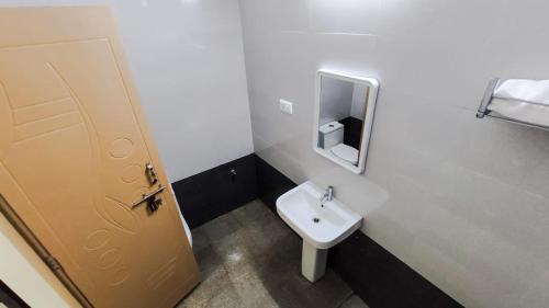 a small bathroom with a sink and a door at Fortune Village Hotel in Kundapur