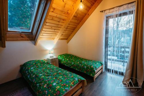 two beds in a room with a window at Chata że HEJ in Bukowiec