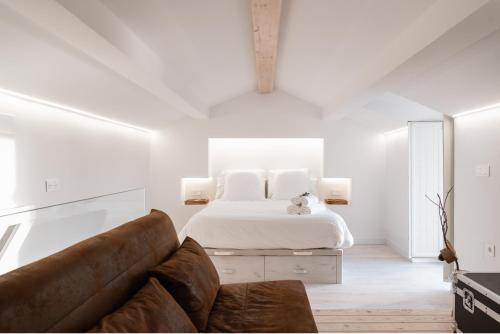 a white bedroom with a bed and a couch at La Casita del Pescador in Ossa de Montiel