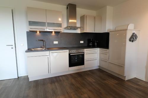 a kitchen with white cabinets and a sink and a refrigerator at UplandParcs Residence Astenberg in Winterberg